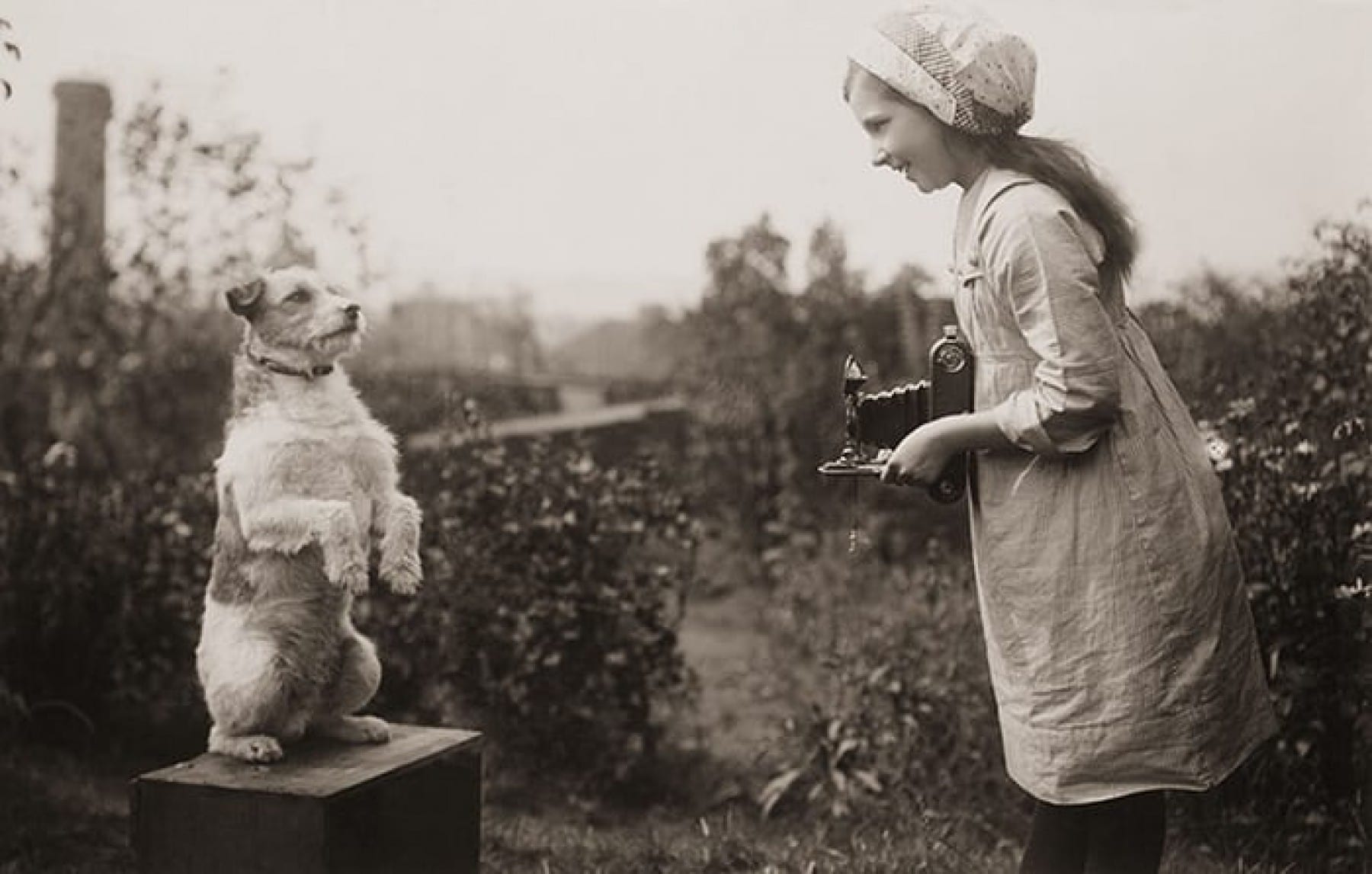 A girl taking a photograph of a dog, 1920’s