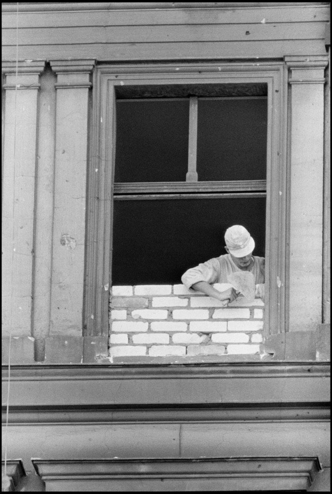 East German Workman Bricking up a window that is due to become part of the wall. West Berlin, Germany, 1961 © Burt Glinn / Magnum Photos