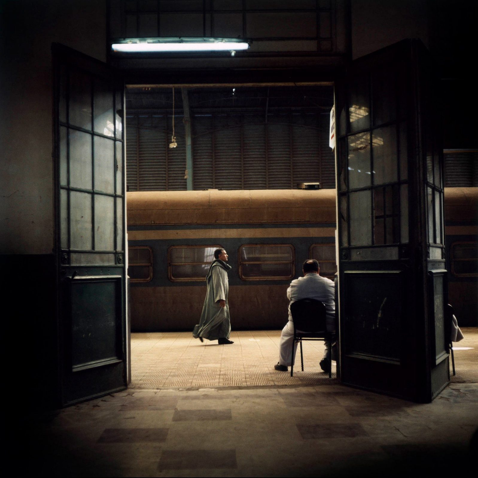A man is walking in Alexandria.s railway station in Egypt - photograph by Denis Dailleux