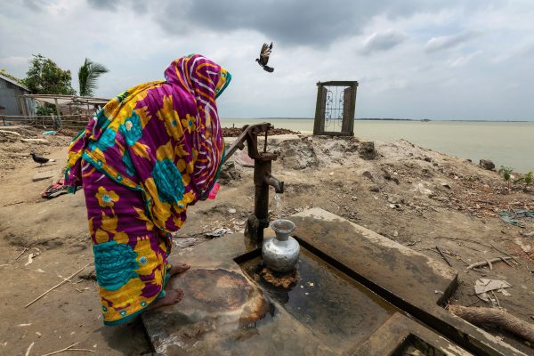 Color photograph of a woman collecting water on eroded land in Bangladesh - Visual Storytelling Award