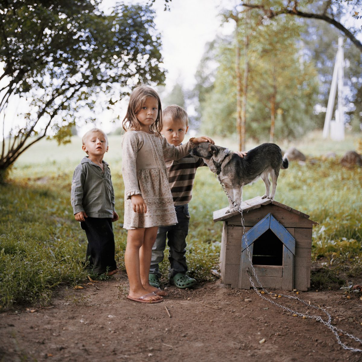 Color photo by Tadas Kazakevičius, from Soon to be Gone, children playing with dog