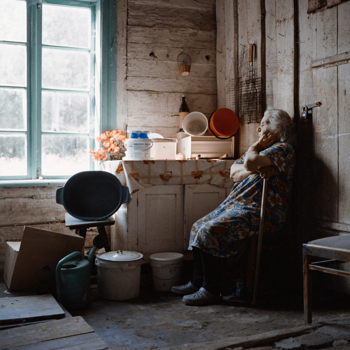 Color photo by Tadas Kazakevičius from Soon to be Gone, elderly woman in house staring out of window.