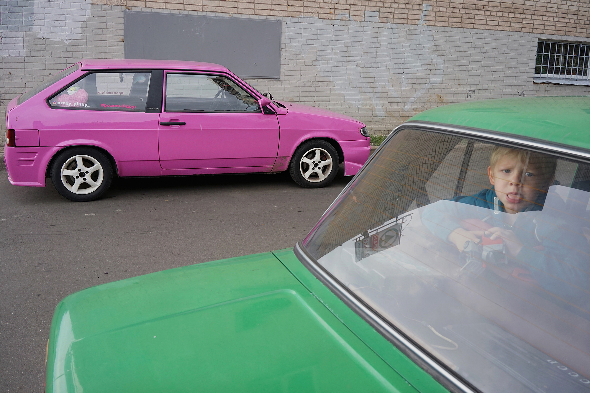 color street photography of pink and green cars and child in Saint Petersburg, Russia by Alexander Sharr