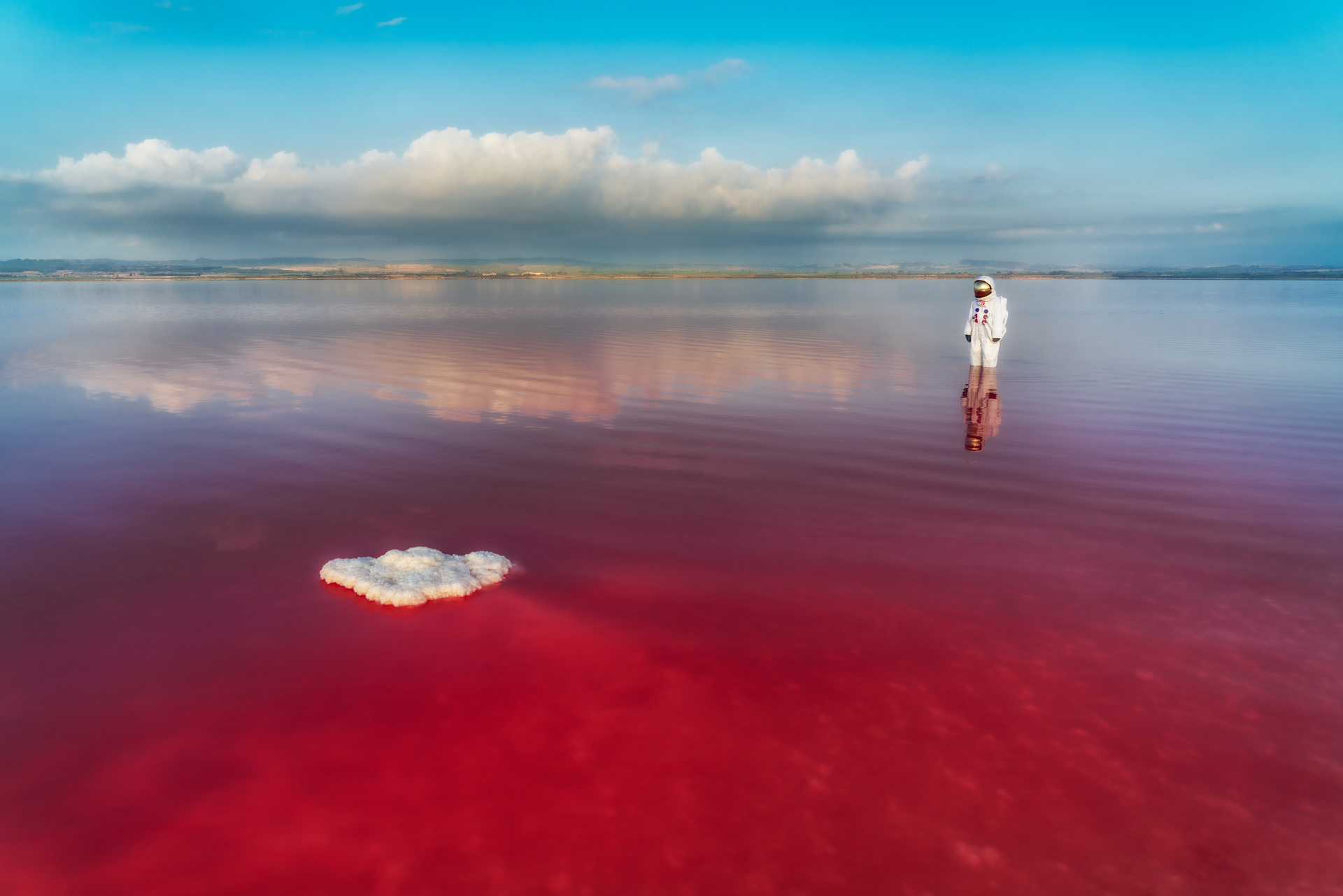 color landscape photograph of an astronaut on pink lake by Jeremy De Backer