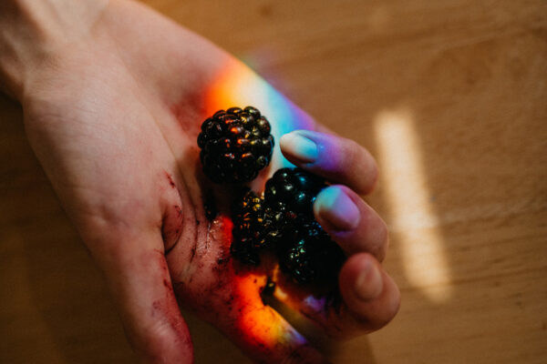 color photo of woman holding berries in her hand by Claire Dam
