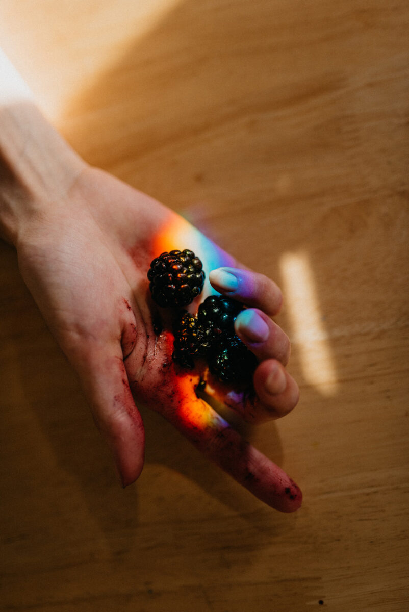 color photo of woman holding berries in her hand by Claire Dam
