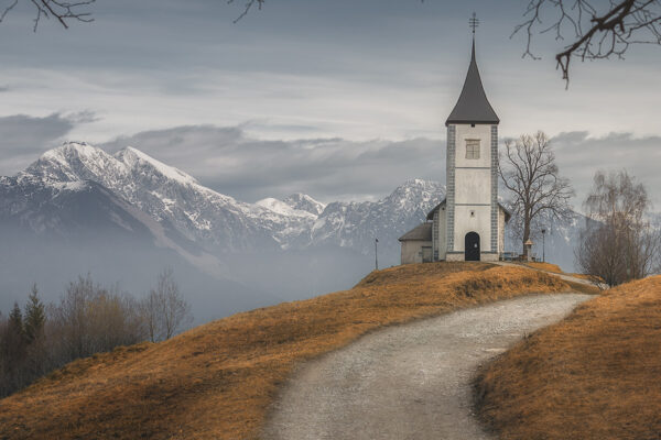color landscape photo of a church and mountains in Slovenia by Thomas de Franzoni