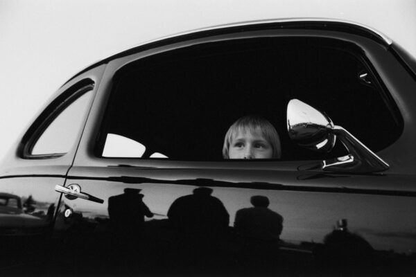 Black and White portrait of young boy in car by Max Marienko