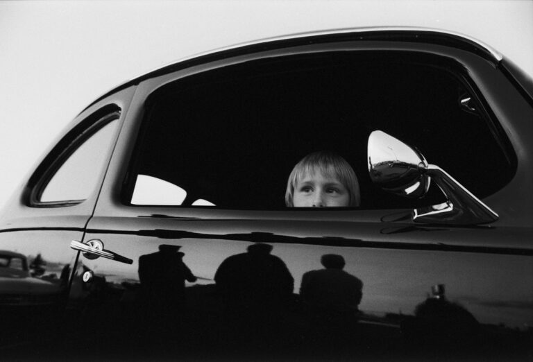 Black and White portrait of young boy in car by Max Marienko