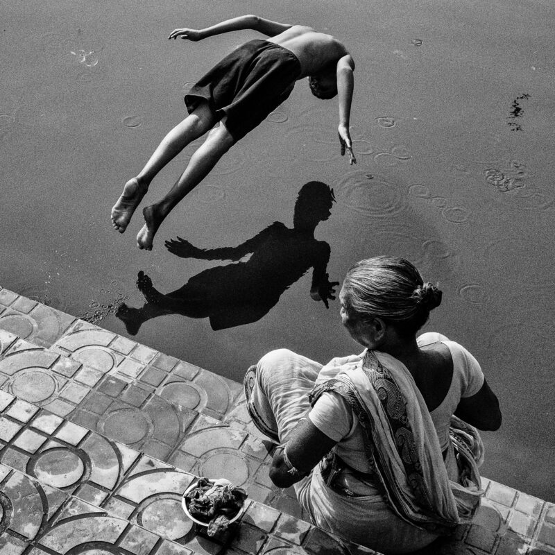 black and white of a boy diving in water in Kolkata, India by Subhran Karmakar