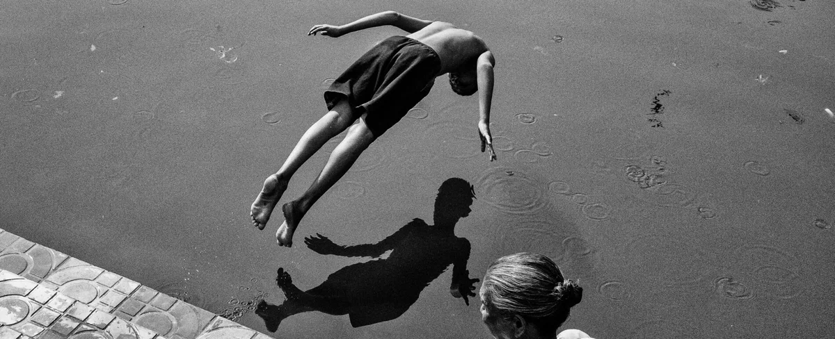 black and white of a boy diving in water in Kolkata, India by Subhran Karmakar