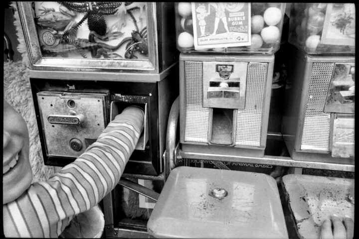 Black and white street photography by Mark Cohen. Boy with hand in candy machine