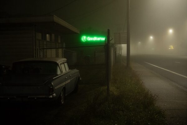 Color landscape photography by Bill Holderfield. Green neon sign next to a parked car and a road at night
