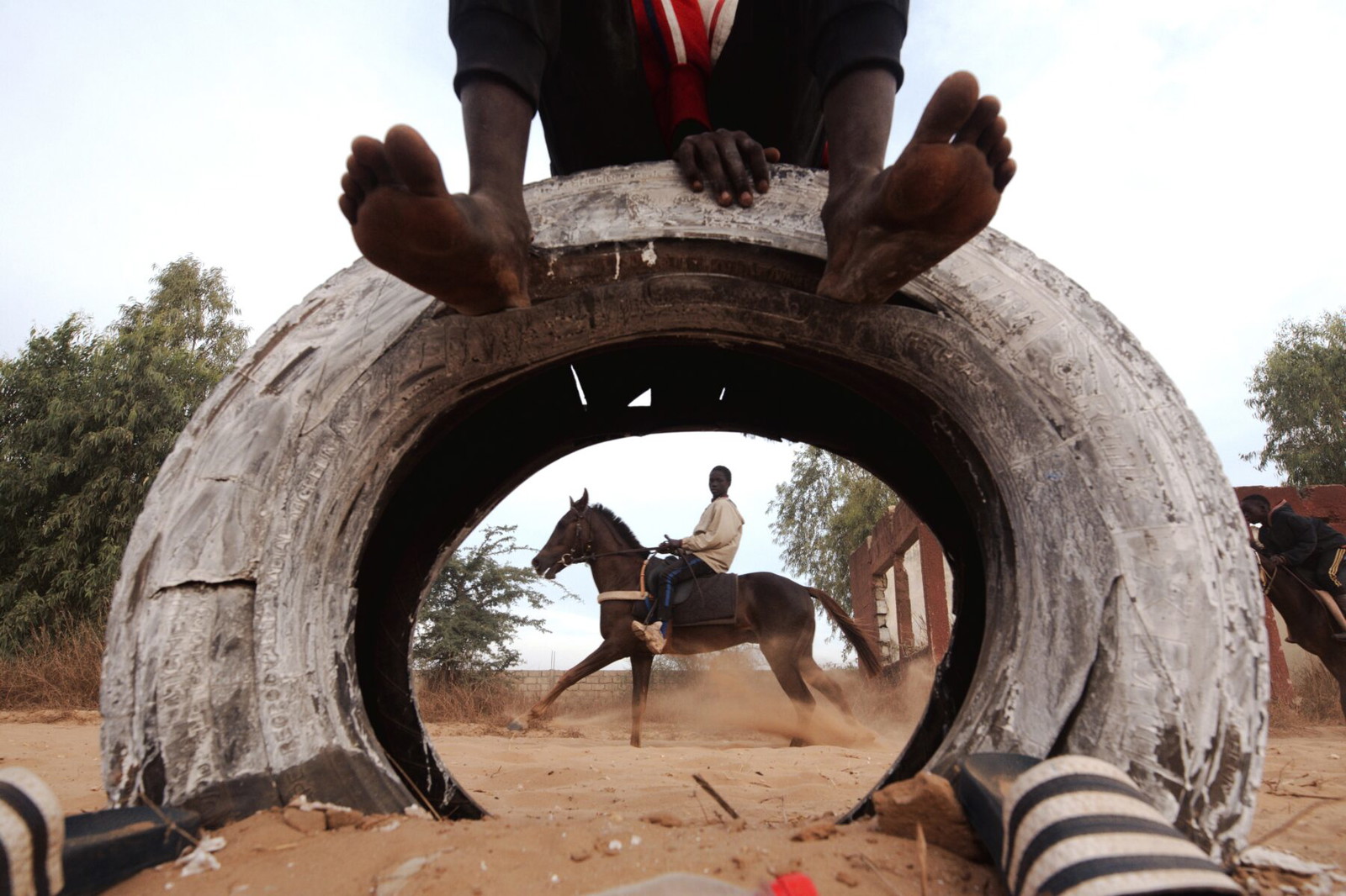 color street photography of young boys riding horses on the outskirts of Dakar by Cooper Inveen