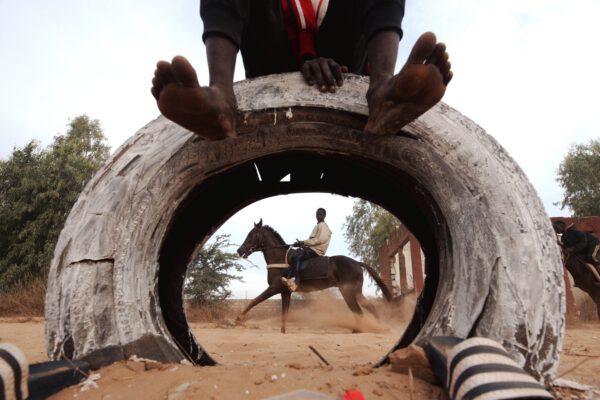 color street photography of young boys riding horses on the outskirts of Dakar by Cooper Inveen