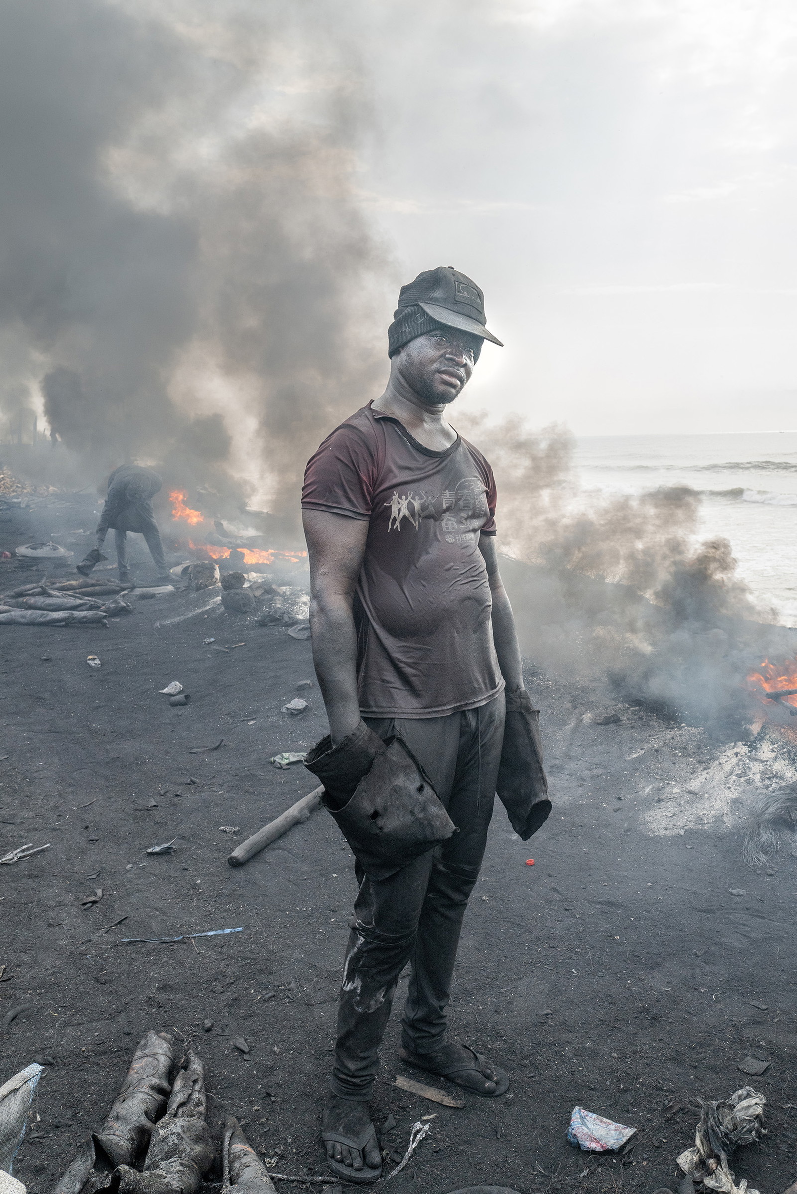 Portrait of a man surroundd by fire and soot in Ghana by Kasia Trojak