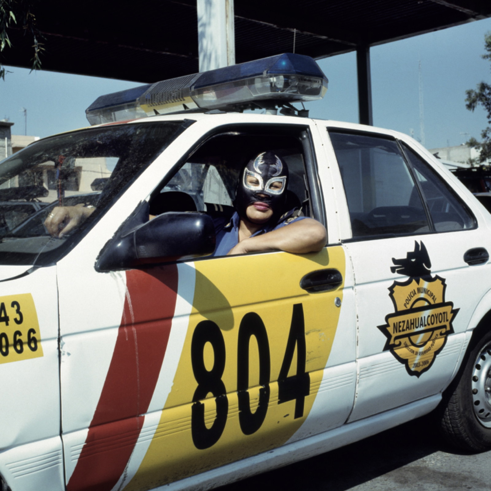 Portrait photography by Lourdes Grobet. Masked female wrestler driving a police car