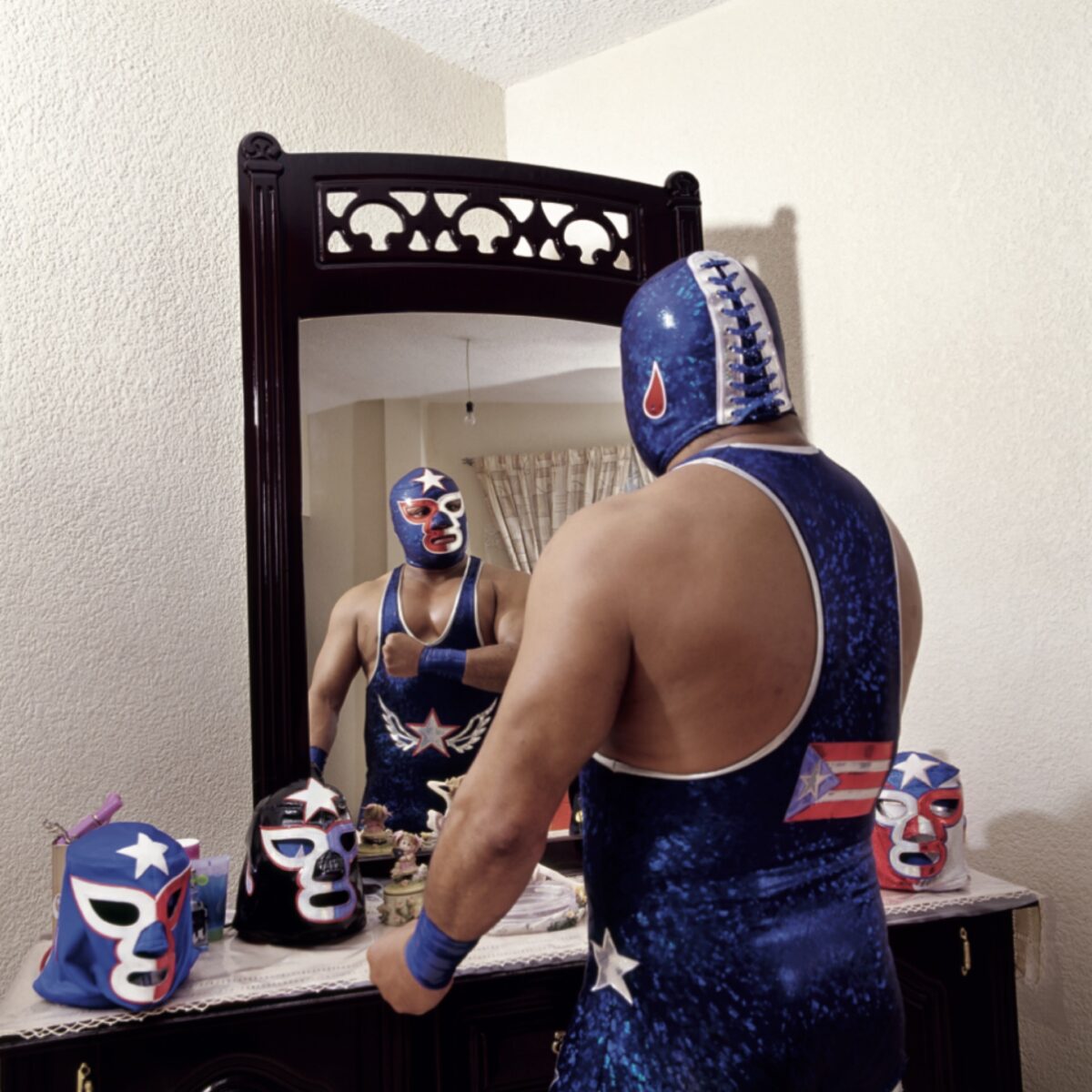 Portrait photography by Lourdes Grobet. Masked wrestler looking in the mirror