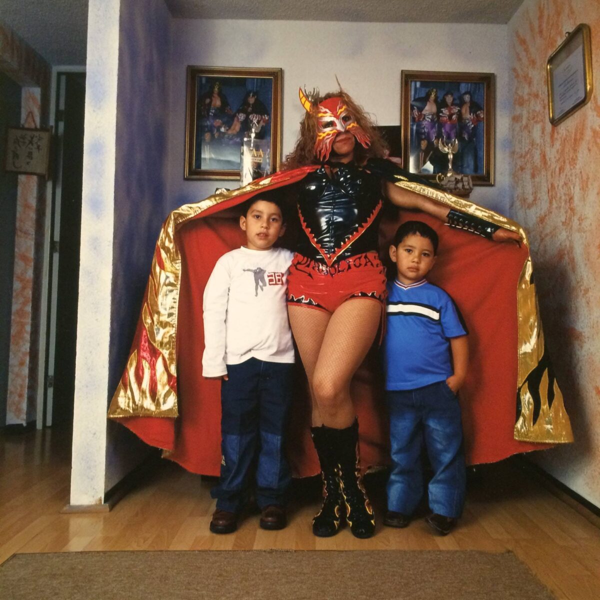 Portrait photography by Lourdes Grobet. Masked female wrestler with her two children at home