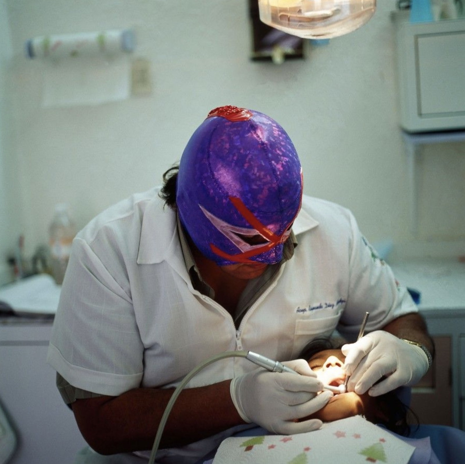Portrait photography by Lourdes Grobet. Dentist in wrestling mask with a patient