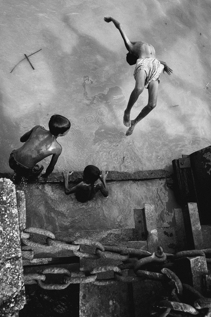 Black and white photo of children playing in water in Yangon, Myanmar, by Gil Kreslavsky