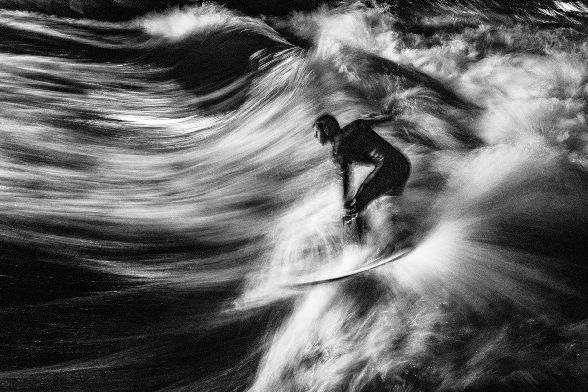 Black and white photo of man surfing in Munich, Germany by Susanne Bartels