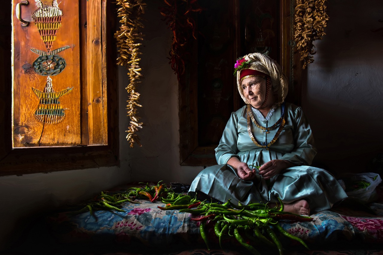 Portrait of a woman preparing chillies in traditional clothes in Turkey by F. Dilek Yurdakul