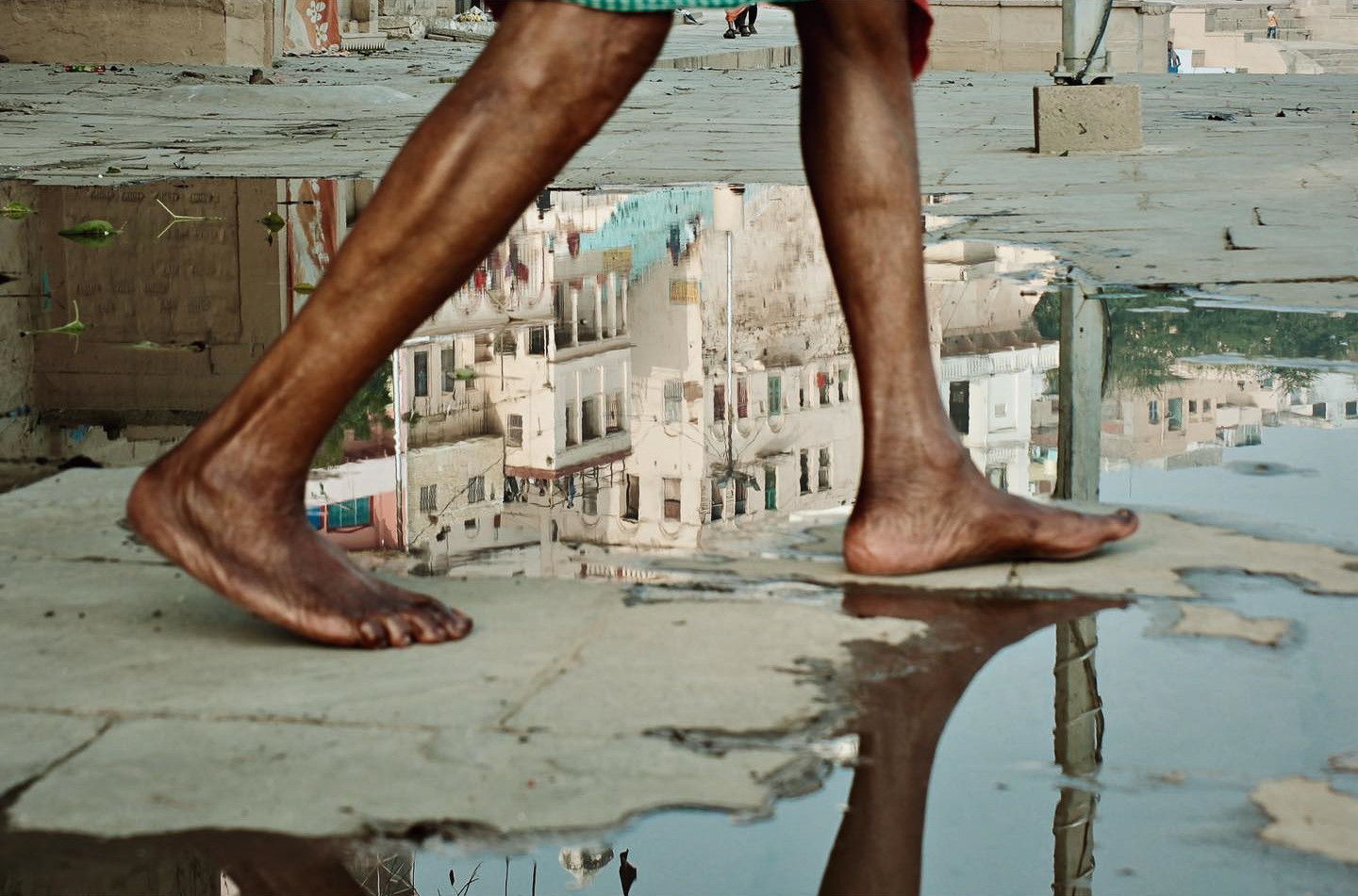Street photography by Gil Kreslavsky. A pair of legs and a reflection in a puddle