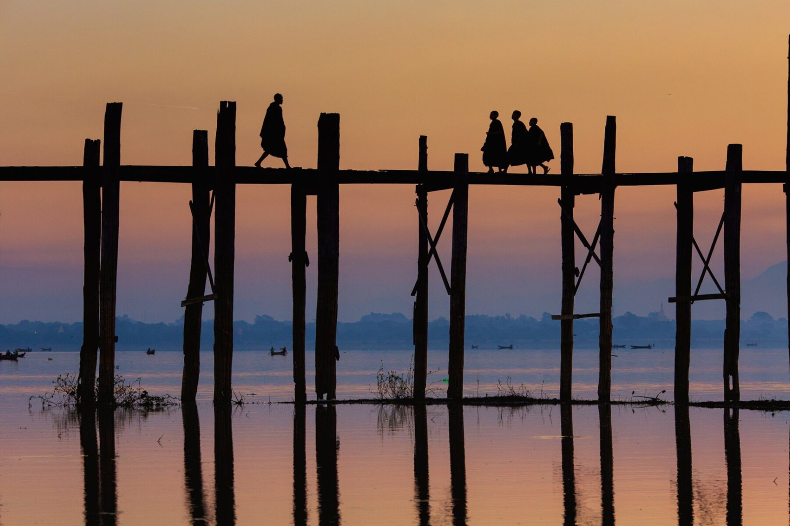 Travel photography by Gil Kreslavsky. Monks crossing a bridge a wooden bridge at sunset