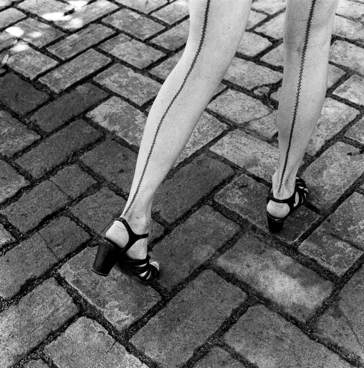 Black & white photography by Graciela Iturbide. Woman's legs in tights and heels