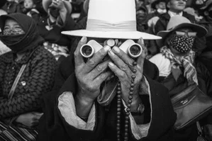 black and white street photography portrait of man holding binoculars in Tibet by Tommy Jiang