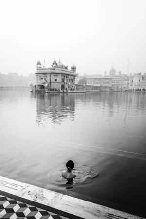 black and white photo of woman bathing in front of temple in India by Ajay Randhawa