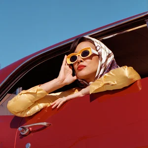 Color portrait fashion photo of woman with sunglasses in red car by