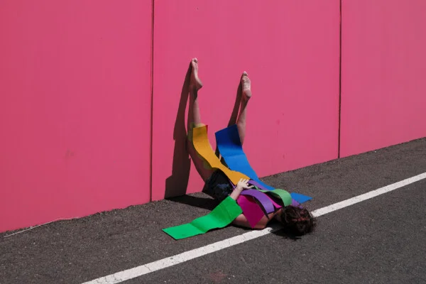Conceptual fine art color portrait of woman against pink wall by Ana Garrido Santos