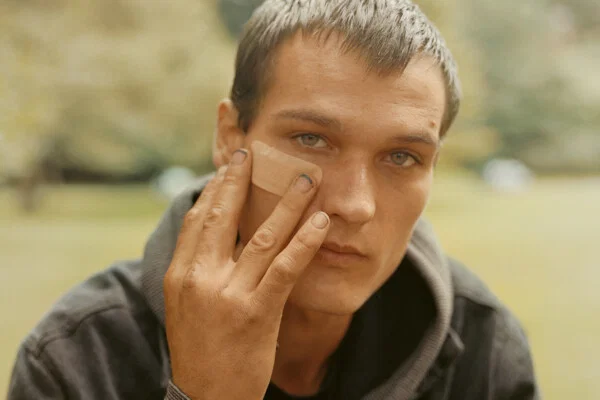 Documentary photography by Gregory Halpern. Portrait of a young man holding a plaster on his face