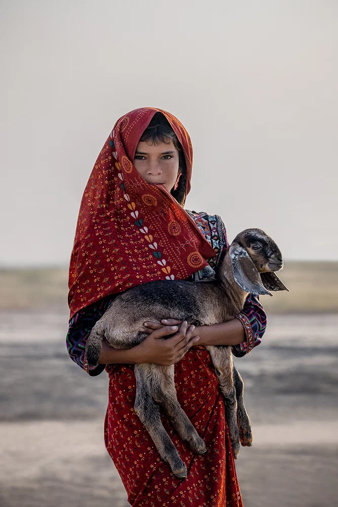 color portrait photo of child holding baby goat in western India by Giovanna Aryafara
