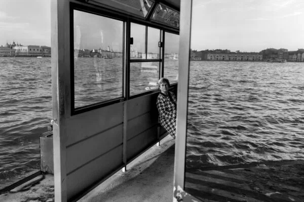 black and white street photo of woman waiting for boat in Venice, Italy by Hadrien Jean-Richard