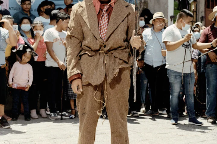 Documentary photography by Juan Brenner. Portrait of a man in a mask with people behind him in Guatemala