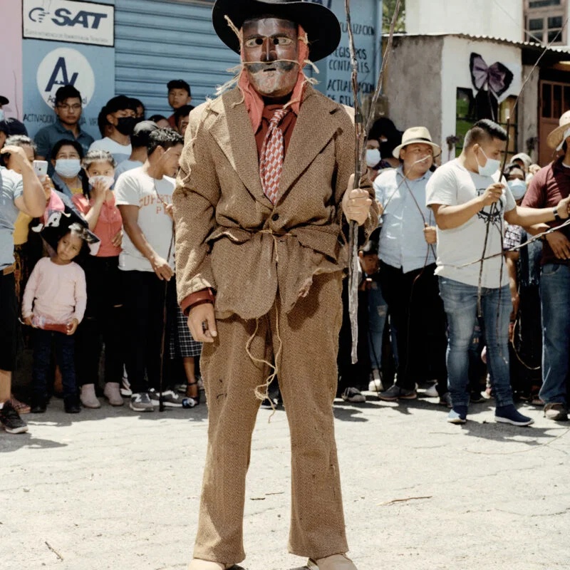 Documentary photography by Juan Brenner. Portrait of a man in a mask with people behind him in Guatemala