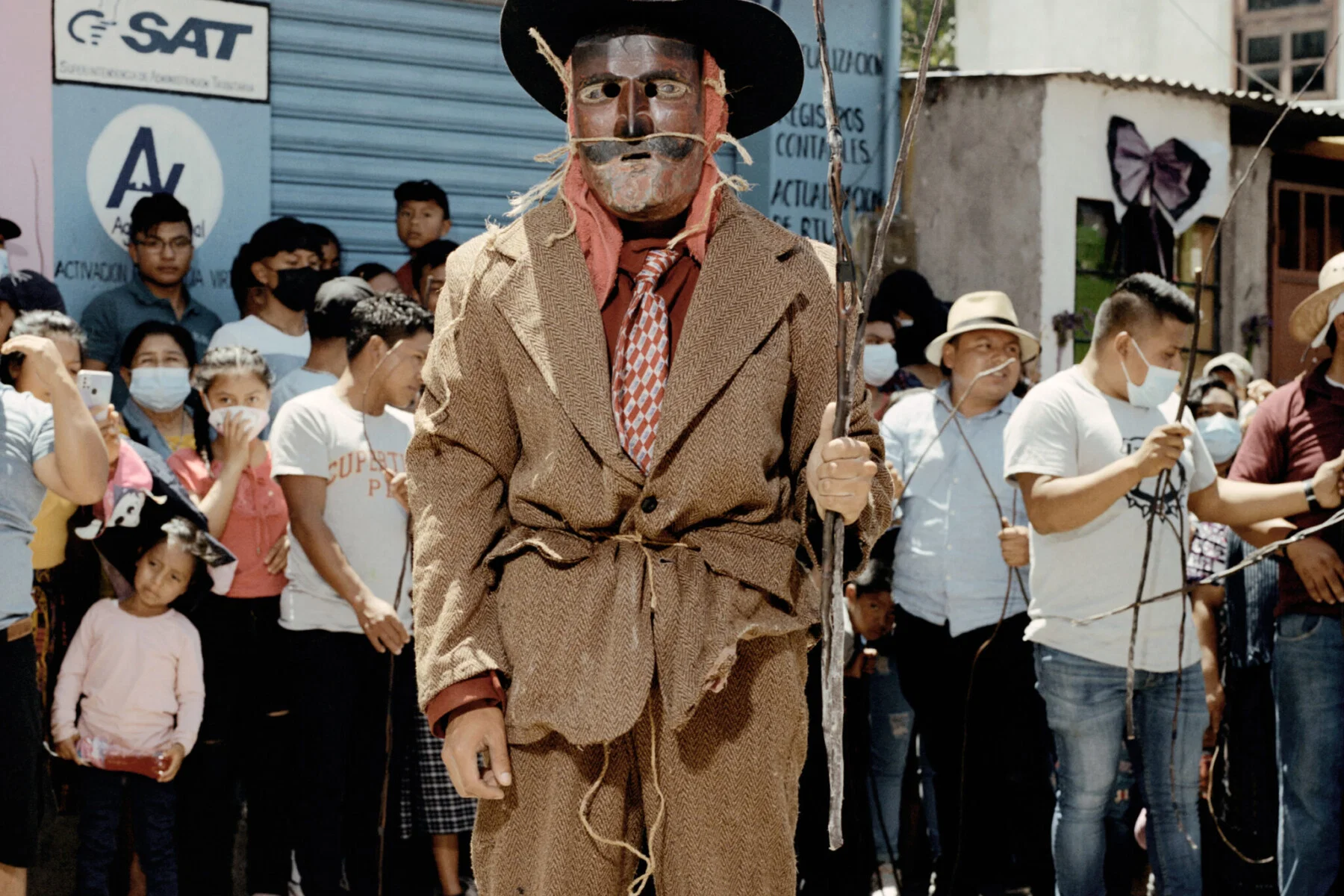 Documentary photography by Juan Brenner. Portrait of a man in a mask with people behind him in Guatemala