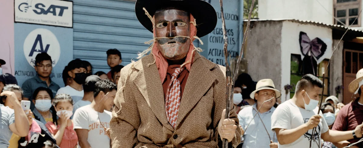 Documentary photography by Juan Brenner. Portrait of a man in a mask with people behind him in Guatemala