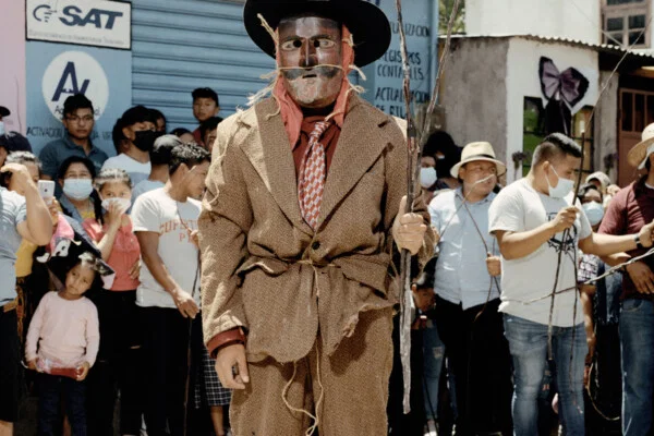 Documentary photography by Juan Brenner. Portrait of a man in a mask with people behind him in Guatemala