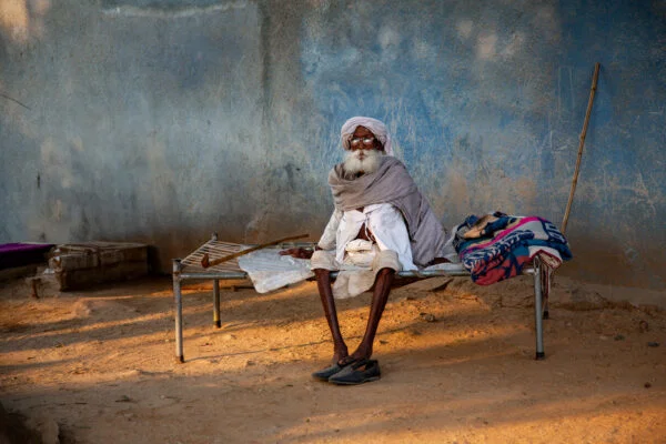Color travel photo portrait of a Rajasthani elder resting on a bed in Varanasi, India by Frances Bruchez