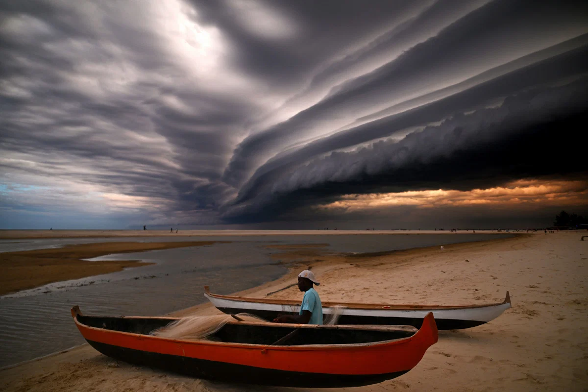 Color landscape photo of man mending fishing nets on the beach in Morondava, Madagascar by Margo Ryan