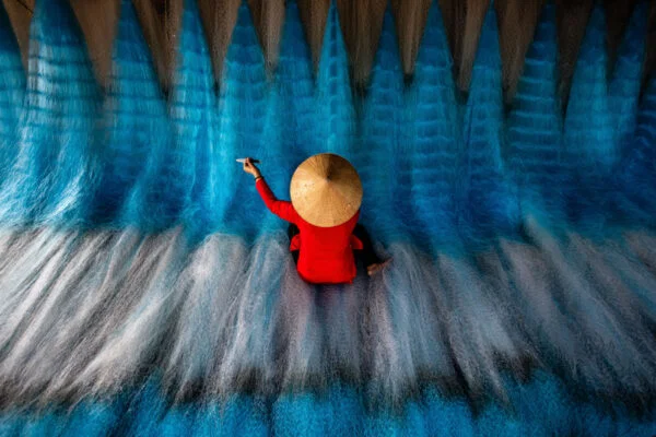 Travel award color photo of woman mending fishing nets in Vietnam by Marie Kent