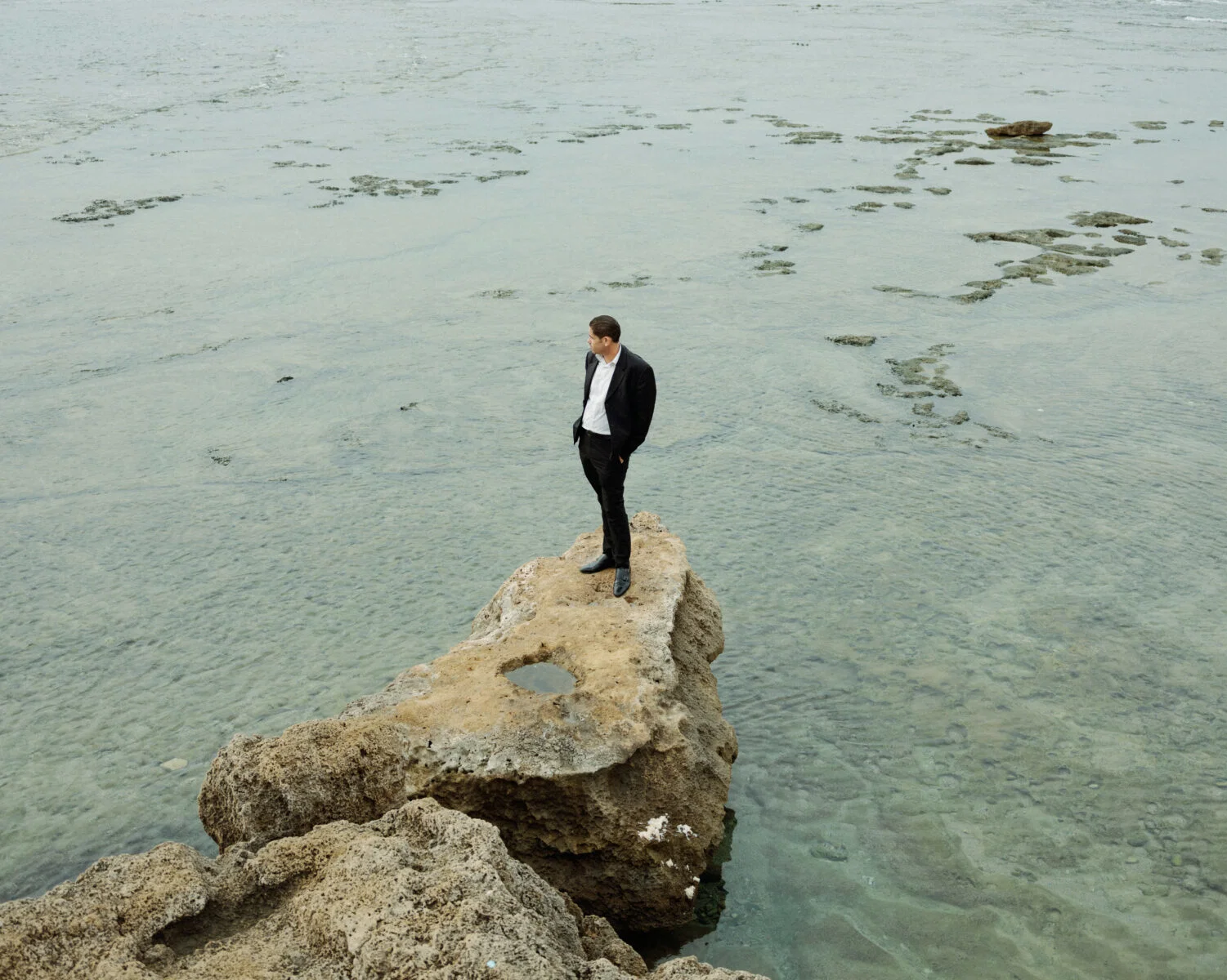 Portrait of a man stood on a rock in front of the sea by Vedad Divovic